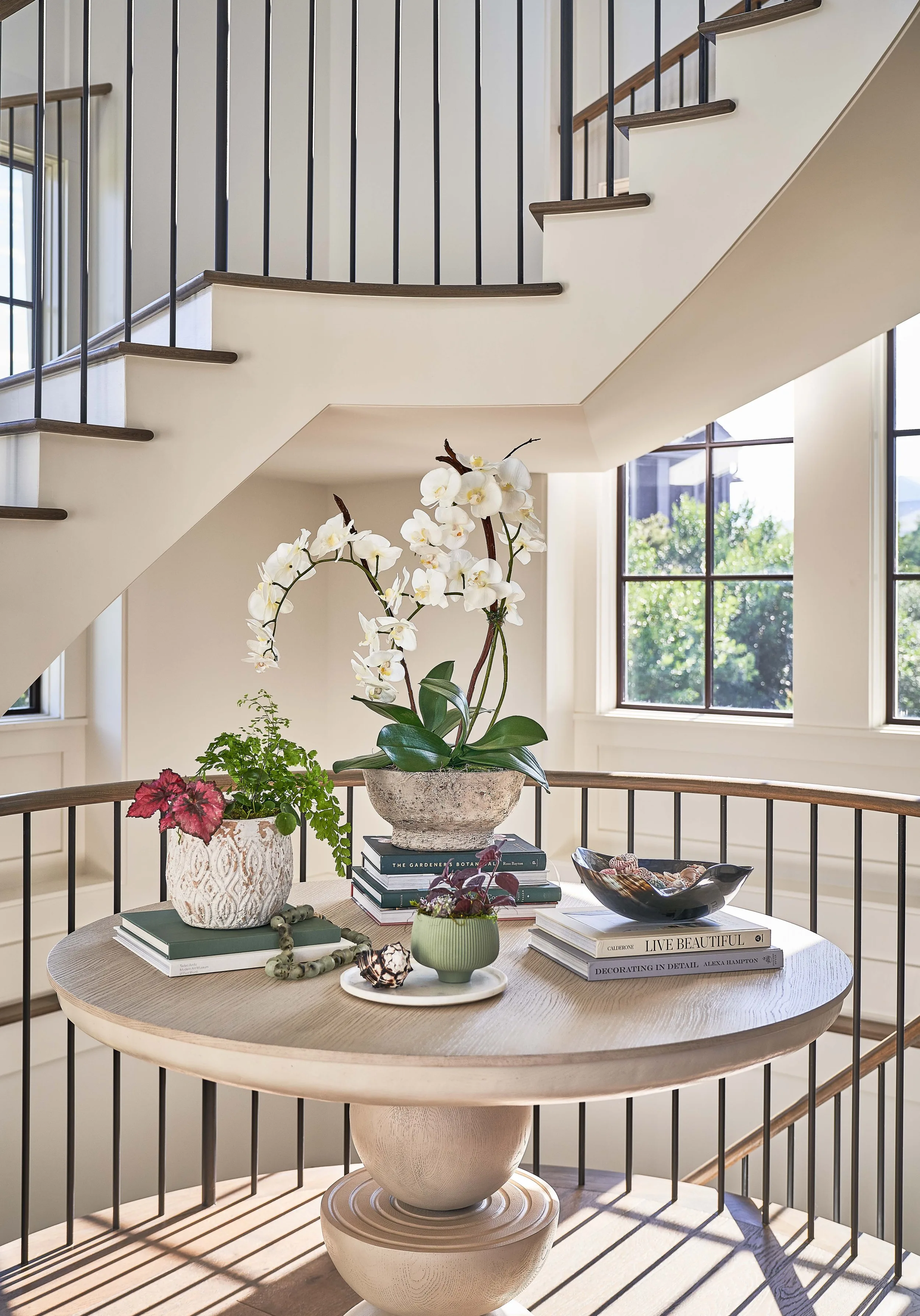 Curved wooden spiral staircase with iron balusters in a Herlong-designed home.