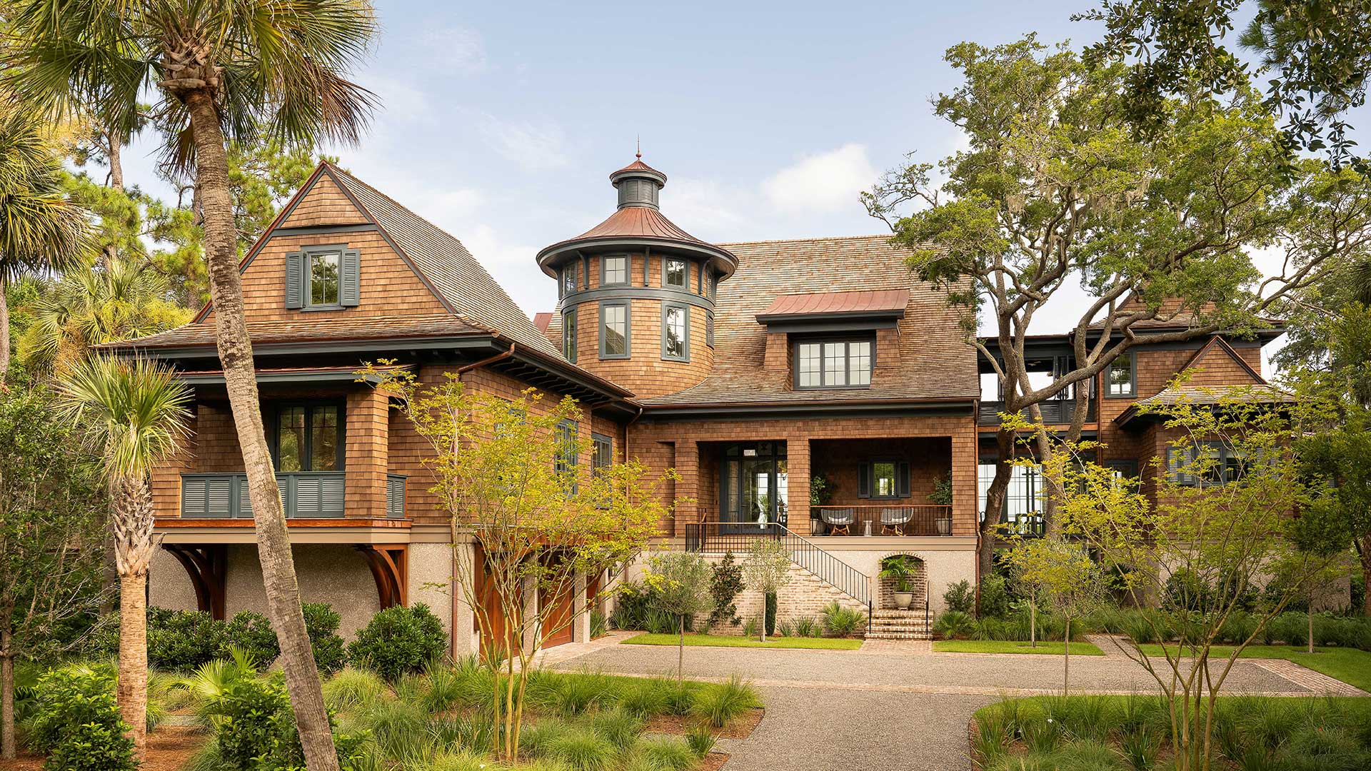 A historic-style home with a brick exterior, multiple gables, and a prominent round turret, framed by trees.