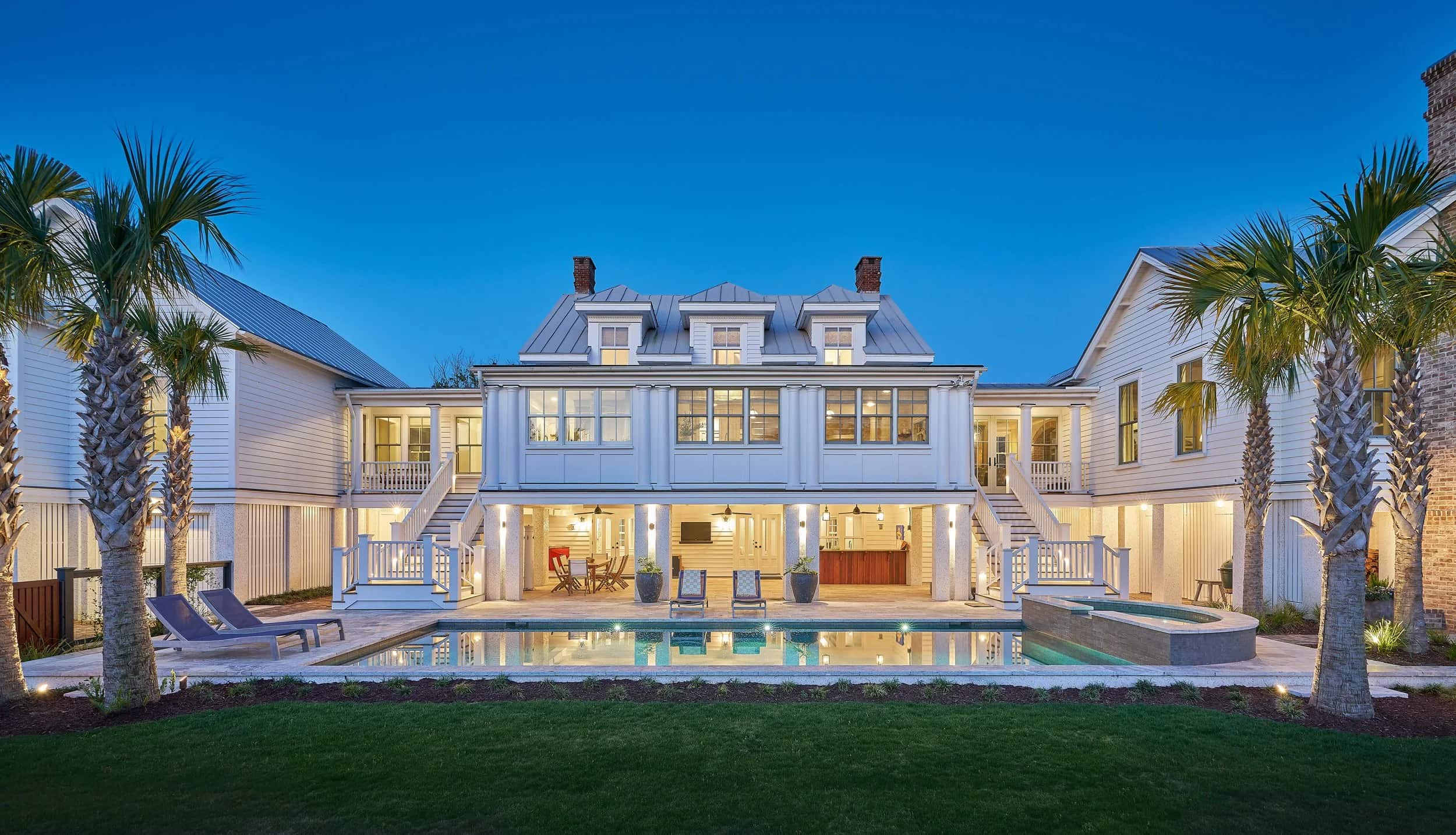 A coastal Herlong home lit at dusk overlooking a pool.
